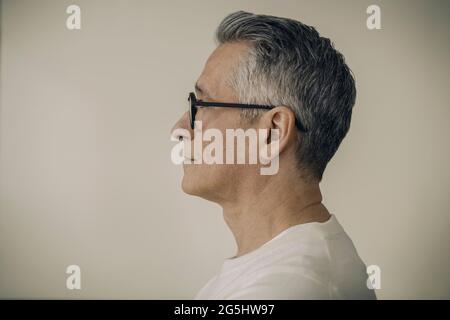 Vista profilo di uomo maturo che indossa occhiali su sfondo beige Foto Stock