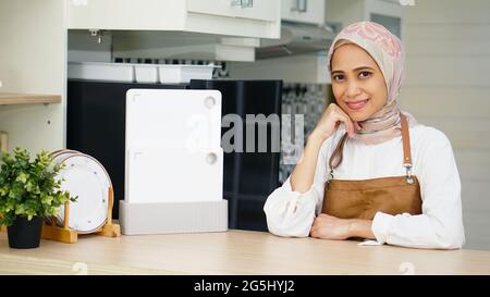 Bella donna asiatica che indossa Hijab e grembiule in cucina Foto Stock