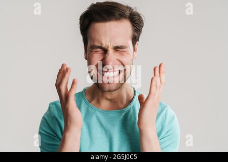 Stressato uomo sconvolto che soffre di una forte emicrania isolato su sfondo grigio Foto Stock