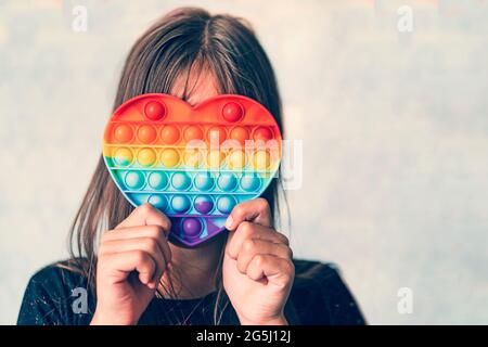 Carino bambino senza volto che gioca con il fidget Pop IT. Push pop bolla flessibile fidget sensoriale giocattolo fornire scarico e sono buone per lo sviluppo di Foto Stock