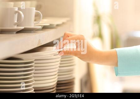 Primo piano di una mano donna che tiene un piatto in cucina Foto Stock