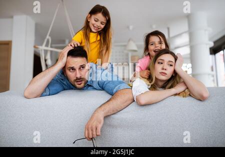 La madre stanca e il padre si sentono seccati mentre rumoroso poco bambini a casa Foto Stock