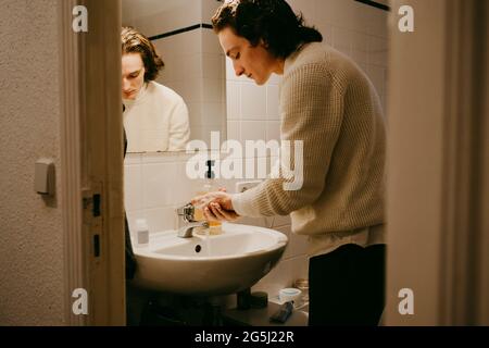Uomo medio adulto che lava le mani in bagno a casa Foto Stock