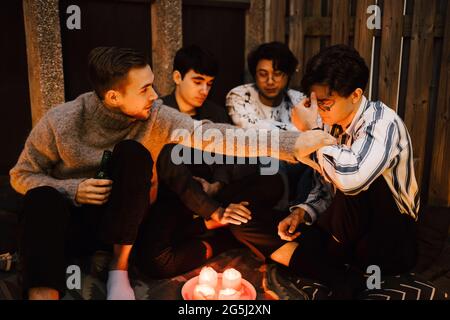 Amici maschi che sostengono l'uomo triste mentre si siede in balcone Foto Stock