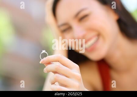 Donna asiatica felice che guarda l'anello di fidanzamento in strada Foto Stock