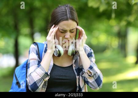 Studente che soffre di mal di testa a piedi in un parco o campus in estate Foto Stock