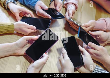 Un gruppo di millennials che tiene i telefoni cellulari nelle loro mani - smartphone nelle mani dei giovani - telefoni moderni nelle mani degli studenti concep Foto Stock