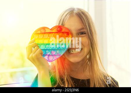 Ragazza ritratto con moderno giocattolo popit. Colorato e luminoso pop it giocattolo semplice concavità. Trendy antistress sensoriale fidget push pop it. Divertente ragazza è nascosto Foto Stock