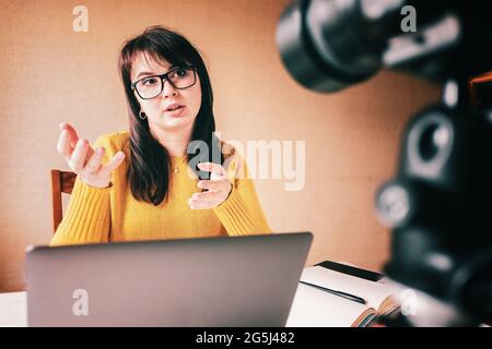 Vlogger registra contenuti per il suo canale - fotocamera su un treppiede e la ragazza comunica attraverso la comunicazione video - Vlogging e la creazione di un video blo Foto Stock