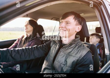 La famiglia viaggia felicemente in auto - mamma papà e un bambino vanno in auto - genitori e un bambino stanno andando sulla strada per l'auto Foto Stock