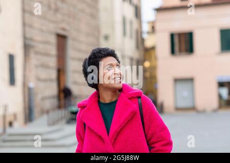 Italia, Toscana, Pistoia, Donna in camice rosa e cuffie che attraversano la città Foto Stock