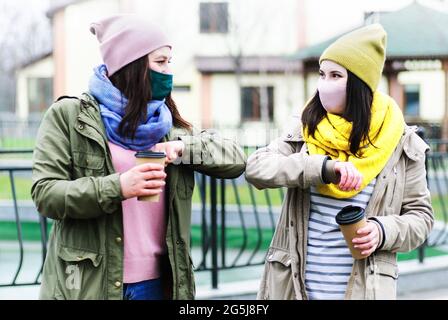 Le ragazze si salutano con i loro gomiti - concetto di una nuova normalità - toccando con un gomito Foto Stock