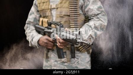 Composizione della sezione centrale del soldato maschio che tiene la pistola, contro il fumo su nero Foto Stock