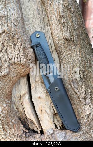 Un coltello in una guaina in pelle. Coltello da caccia in una custodia in pelle. Coltello su sfondo di legno. Foto Stock