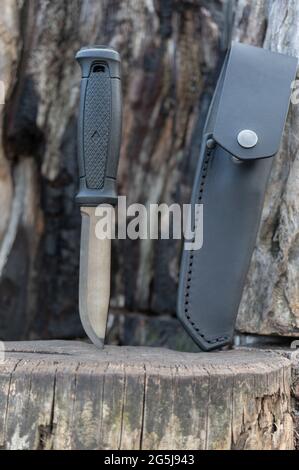 Coltello di caccia a lama fissa. Coltello e guaina in pelle. Coltello su sfondo di legno bruciato. Foto Stock