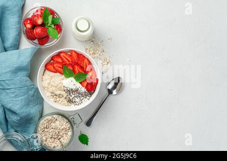 Porridge di farina d'avena con fragole e semi di chia su sfondo grigio. Foto Stock