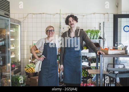 Giovane imprenditore maschile in piedi da donna proprietario in negozio Foto Stock