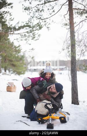 Ragazze allegre che giocano con il padre sulla neve durante le vacanze Foto Stock