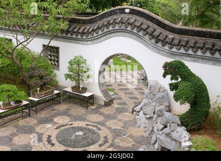 Archway cinese con disegno di uccelli e pipistrelli ciottoli, bonsai sui tavoli Foto Stock