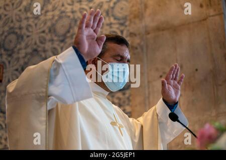 Sacerdote cattolico che indossa una maschera mentre celebra la messa durante la pandemia di COVID Foto Stock