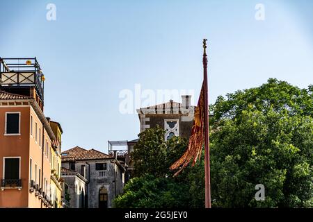 Bandiera con stemma di Venezia, Italia che vola su un flagpole. Scena estiva su una piazza in Italia Foto Stock