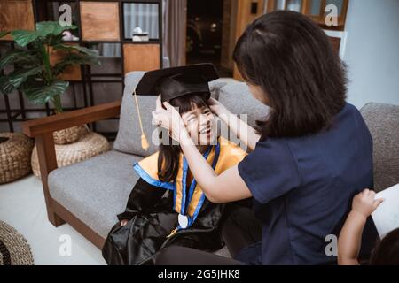 Madre e bambino asiatici che si preparano nel suo giorno di laurea più parente a casa Foto Stock