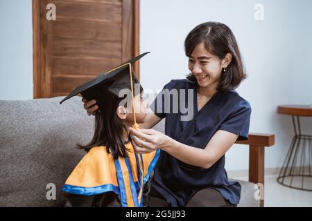 Madre e bambino asiatici che si preparano nel suo giorno di laurea più parente a casa Foto Stock