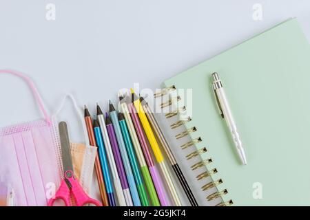 Maschere mediche sul covid-19 coronavirus una varietà di cancelleria colorata diversa in stand su una scuola fornisce la posa piatta Foto Stock