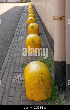 molti blocchi di cemento gialli in una fila in una strada Foto Stock