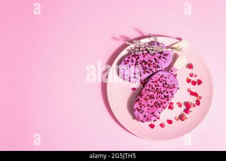 Gelato ai petali di lavanda e rosa, dolce freddo. Luce dura alla moda, ombra scura. Sfondo rosa pastello, vista dall'alto Foto Stock