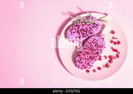 Gelato ai petali di lavanda e rosa, dolce freddo. Luce dura alla moda, ombra scura. Sfondo rosa pastello, vista dall'alto Foto Stock