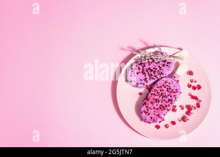 Gelato ai petali di lavanda e rosa, dolce freddo. Luce dura alla moda, ombra scura. Sfondo rosa pastello, vista dall'alto Foto Stock