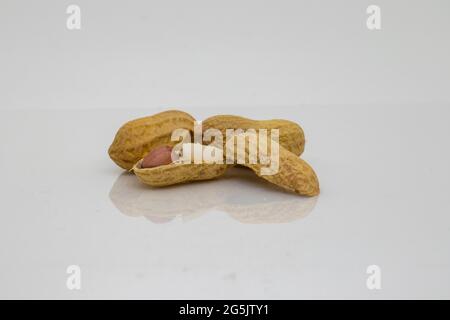 Arachidi. Dadi arrostiti isolati su sfondo bianco con superficie riflettente. Foto Stock