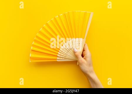 Mano che tiene ventilatore di mano fatto di bambù e carta Foto Stock