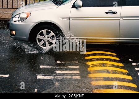 Guidare un'auto in giro per la città durante una pioggia battente. Foto Stock