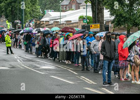 WIMBLEDON LONDRA 28 giugno 2021. Lunghe file di tifosi di tennis che si accodano sotto la pioggia al mattino per entrare nei campi prima dell'inizio del gioco il giorno uno delle navi Wimbledon Championshionship. Il torneo dell'anno scorso è stato annullato a causa della pandemia del Covid-19 per la prima volta dalla seconda guerra mondiale e si svolgerà dal 28 giugno al 11 luglio con una capacità ridotta del 50% e saranno ammessi solo gli spettatori con biglietti preordinati e non sarà consentito fare la coda o il campeggio. Credit amer Ghazzal/Alamy Live News Foto Stock