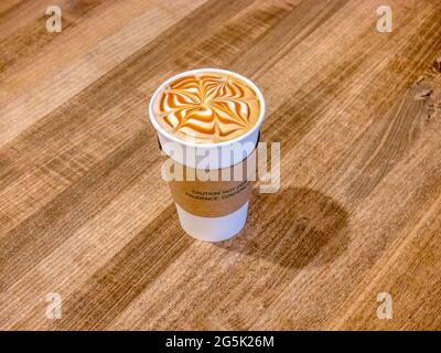 Tappo medio di cappuccino al caramello su tavola in legno Foto Stock