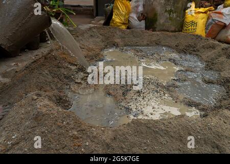 Kolkata, Bengala Occidentale, India - 6th Gennaio 2020 : lavoro indiano che mescola cemento ed acqua manualmente sul pavimento usando una pala. Immagine stock. Foto Stock