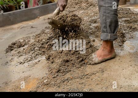 Kolkata, Bengala Occidentale, India - 6th Gennaio 2020 : lavoro indiano che mescola cemento ed acqua manualmente sul pavimento usando una pala. Immagine stock. Foto Stock