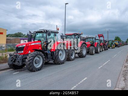 27 Giugno 2021 - Pocklington, East Yorkshire, UK - Beacon Young Farmers Club Tractor Run. Una linea di trattori rossi Massey Ferguson parcheggiati a lato del roa Foto Stock