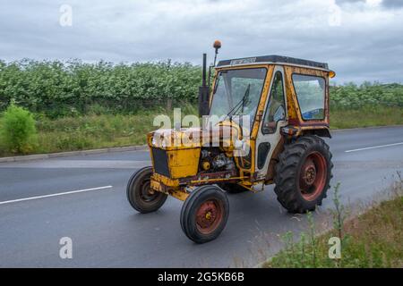 27 Giugno 2021 - Pocklington, East Yorkshire, UK - Beacon Young Farmers Club Tractor Run. Trattore giallo vecchio e arrugginito su strada. Foto Stock
