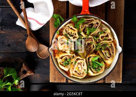 Involtini di pasta di carne con carne o gnocchi pigri in una padella di ghisa su un vecchio fondo rustico di legno. Vista dall'alto Foto Stock