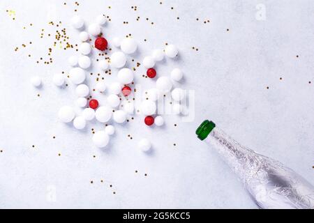 Bottiglia di champagne natalizio con spruzzini di colore bianco su sfondo bianco. Concetto di anno nuovo. Vista dall'alto Foto Stock