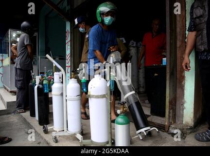 Giacarta, Giacarta, Indonesia. 28 Giugno 2021. La fila dei residenti per il riempimento di bombole di gas ossigeno a Manggarai, Giacarta, il 28 giugno 2021. La domanda di nuove bombole di ossigeno e di riempimento di bombole di ossigeno è aumentata drasticamente a seguito dell'aumento dei casi di Covid-19 nel DKI Jakarta e attualmente le bombole di ossigeno stanno diventando scarse sul mercato, cosicché il rifornimento di ossigeno è anche un'opzione anche se i residenti devono fare la coda. Credit: Dasril Roszandi/ZUMA Wire/Alamy Live News Foto Stock