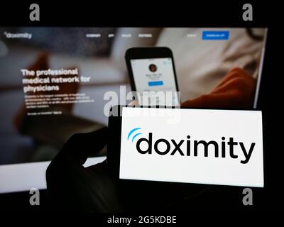 Persona che tiene il telefono mobile con il logo della piattaforma medica americana di rete Doximity Inc. Sullo schermo davanti alla pagina web. Mettere a fuoco il display del telefono. Foto Stock