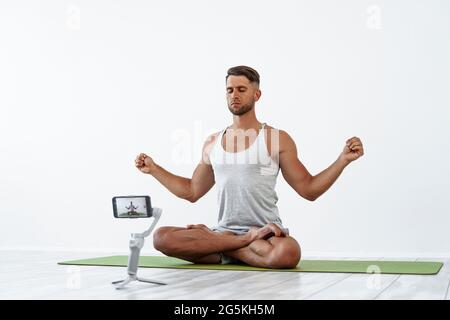 Fit caucasico maschio registrare un blog o lo streaming yoga allenamento. Foto Stock