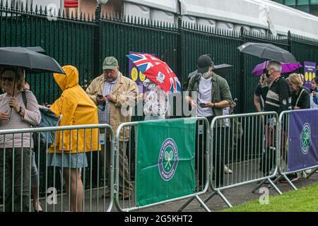 WIMBLEDON LONDRA 28 giugno 2021. Lunghe file di tifosi di tennis che si accodano sotto la pioggia al mattino per entrare nei campi prima dell'inizio del gioco il giorno uno delle navi Wimbledon Championshionship. Il torneo dell'anno scorso è stato annullato a causa della pandemia del Covid-19 per la prima volta dalla seconda guerra mondiale e si svolgerà dal 28 giugno al 11 luglio con una capacità ridotta del 50% e saranno ammessi solo gli spettatori con biglietti preordinati e non sarà consentito fare la coda o il campeggio. Credit amer Ghazzal/Alamy Live News Foto Stock