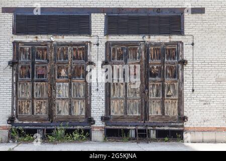 Grandi vecchie porte in legno in un edificio in mattoni per la manutenzione delle comunicazioni elettriche. Foto Stock