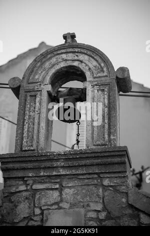 Scala di grigi verticale di una struttura in pietra arcuata con campana in Dalmazia, Croazia Foto Stock