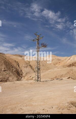 Pilone ad alta tensione di fronte alla catena montuosa con cielo blu nel deserto di Negev, Israele, Asia Foto Stock